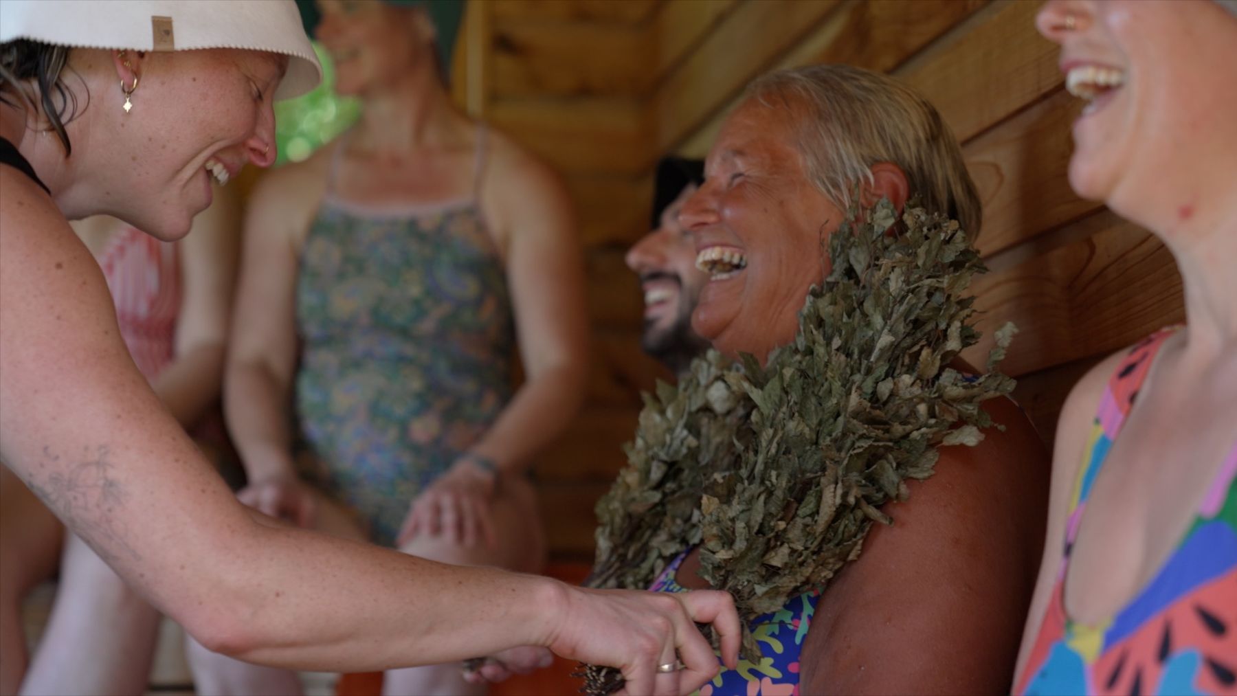 a person laughing in the sauna when recieving birch whisks on the body