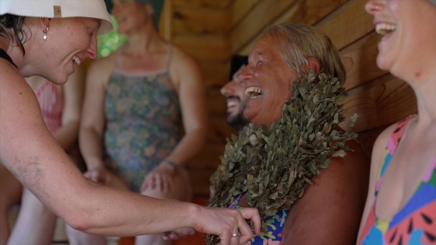 a person laughing in the sauna when recieving birch whisks on the body