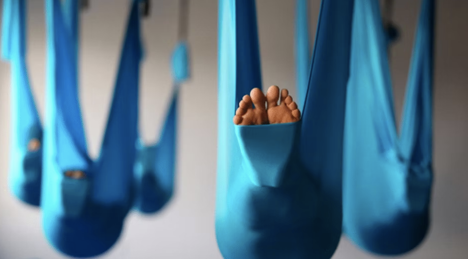a person lying in an aerial yoga hammock