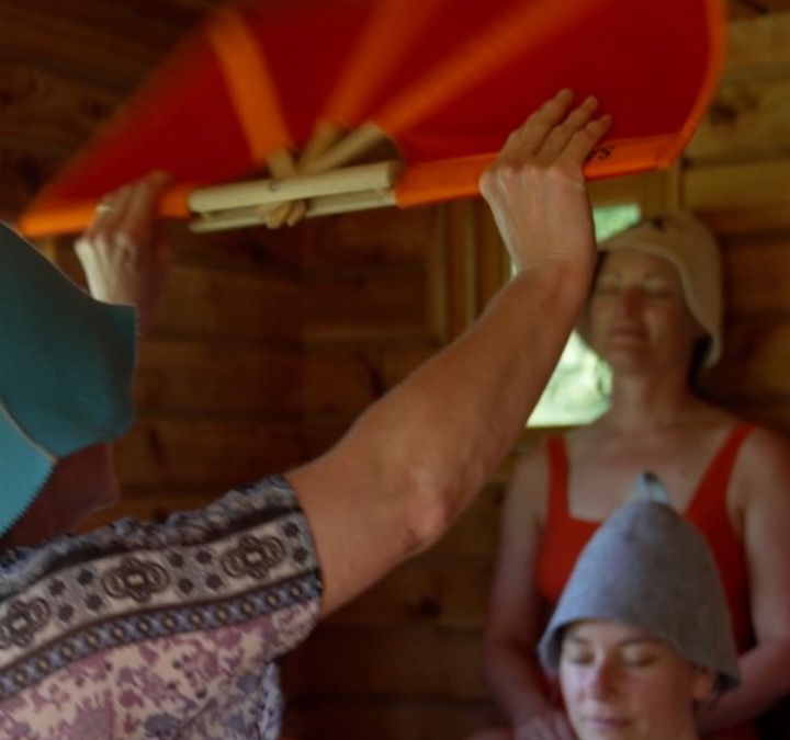 A person waving a sauna fan in a sauna 