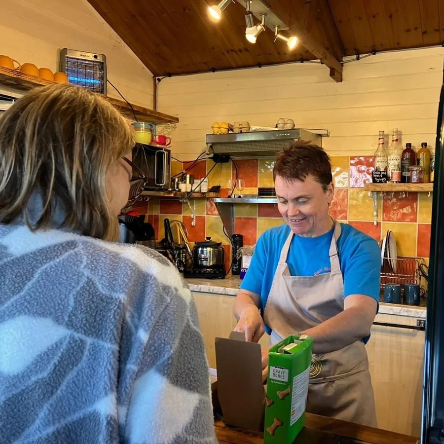 Serving a customer at the tiled counter of the Fika Café, Court Farm Lakes