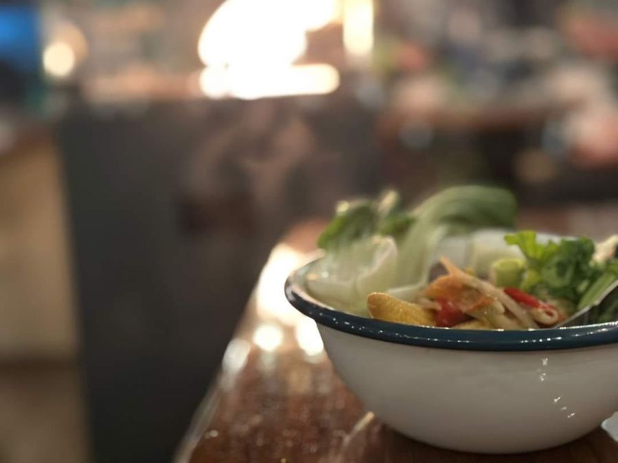 A steaming noodle bowl on the table by the log burner in the café, Court Farm Lakes