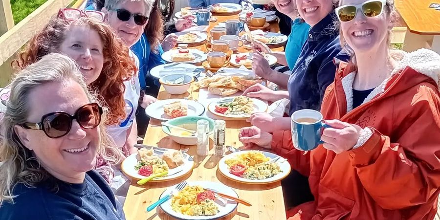 A long table of swimmers eating lunch outside the café, Court Farm Lakes