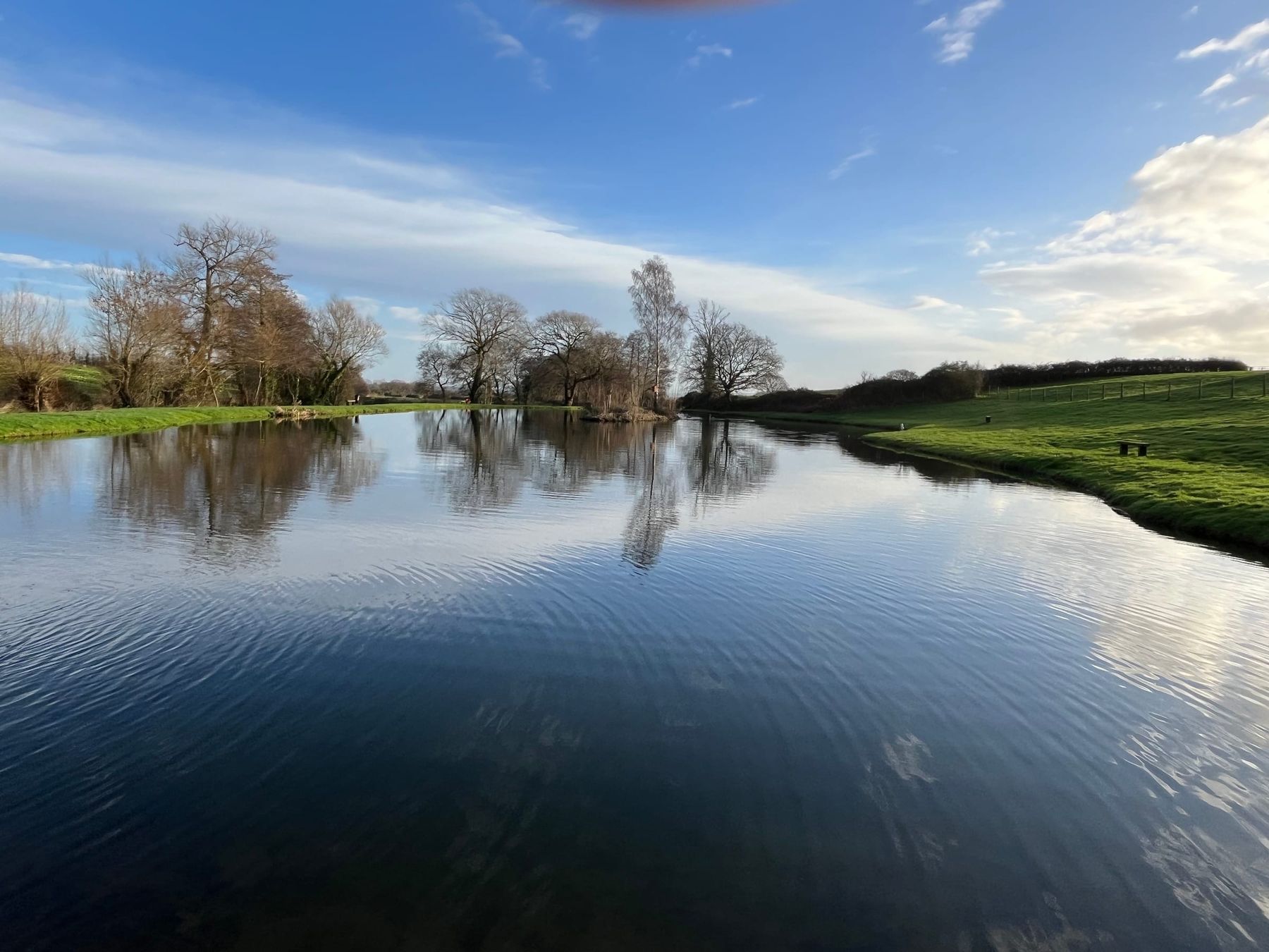 The lake, still and blue under a clear sky, at Court Farm Lakes