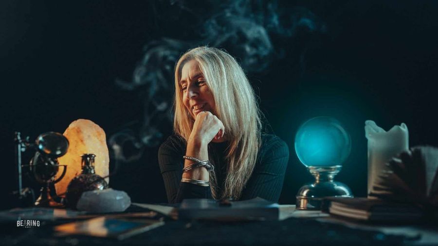 a person sitting at a table with a crystal ball & Smoke
