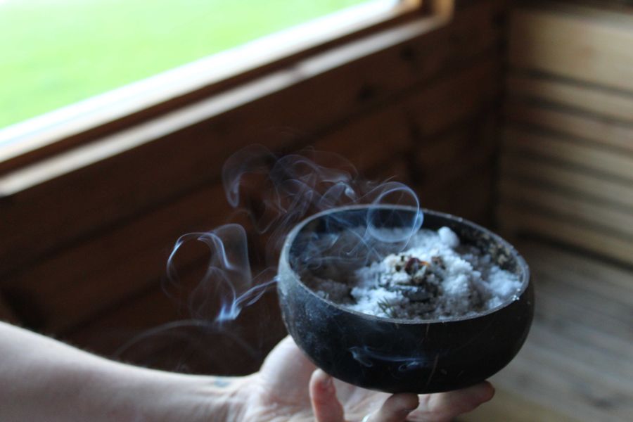 a person holding a bowl with a burning charcoal disk 