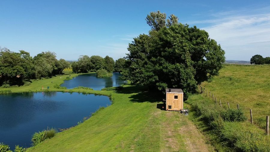 The lake and the wood-fired sauna on the bank from the air, Court Farm Lakes