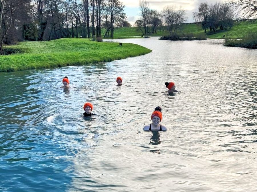 Swimmers in orange bobble hats in the lake at Court Farm Lakes